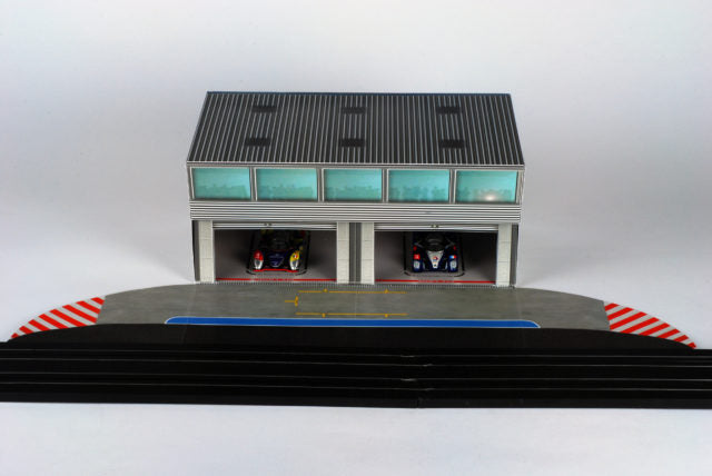 Scale pit building with two garage bays and a track section for AFX RaceMaster 1070