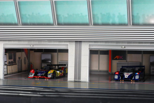 Scale model pit building with race cars parked in bays for AFX RaceMaster 1070