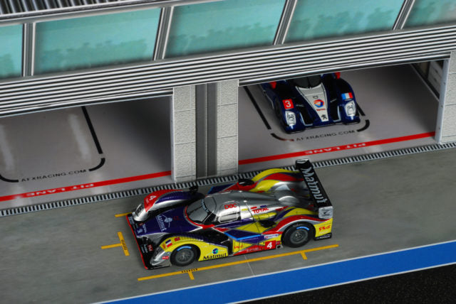 Race car parked in a pit stall within a miniature pit building for AFX RaceMaster 1070