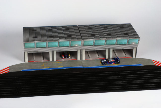 Scale pit building with garage bays and race cars on a track section for AFX RaceMaster 1070