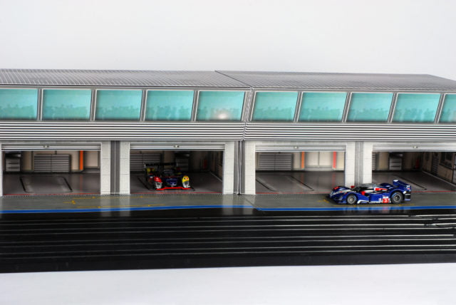 Scale pit building with two race cars parked in the bays for AFX RaceMaster 1070