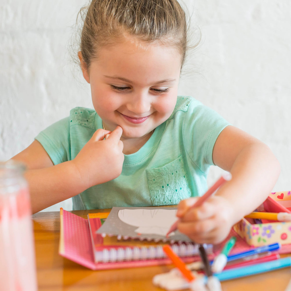Young girl colors at a table with a coloring set for Schylling 14014