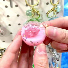 Pink, sleeping animal key charm held in hands against a backdrop of other charms for BC Mini 12056