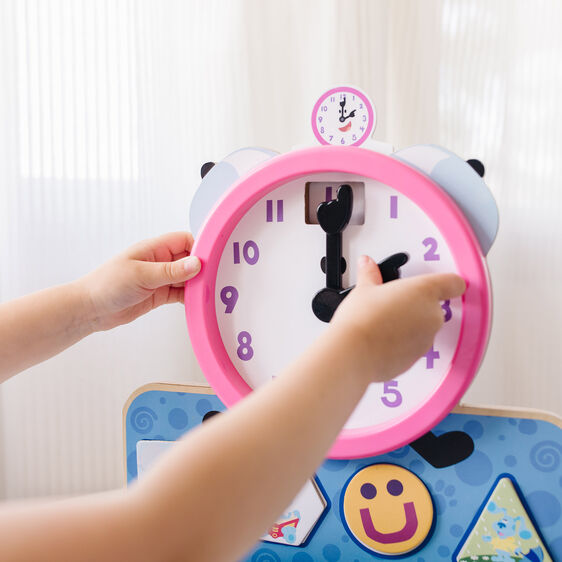 Child's hands adjust a colorful, educational clock toy for Melissa and Doug 33014