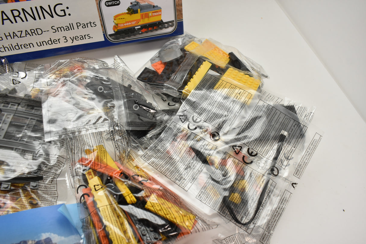 Plastic bags containing train track and vehicle pieces for play for Electric Train AUS25827