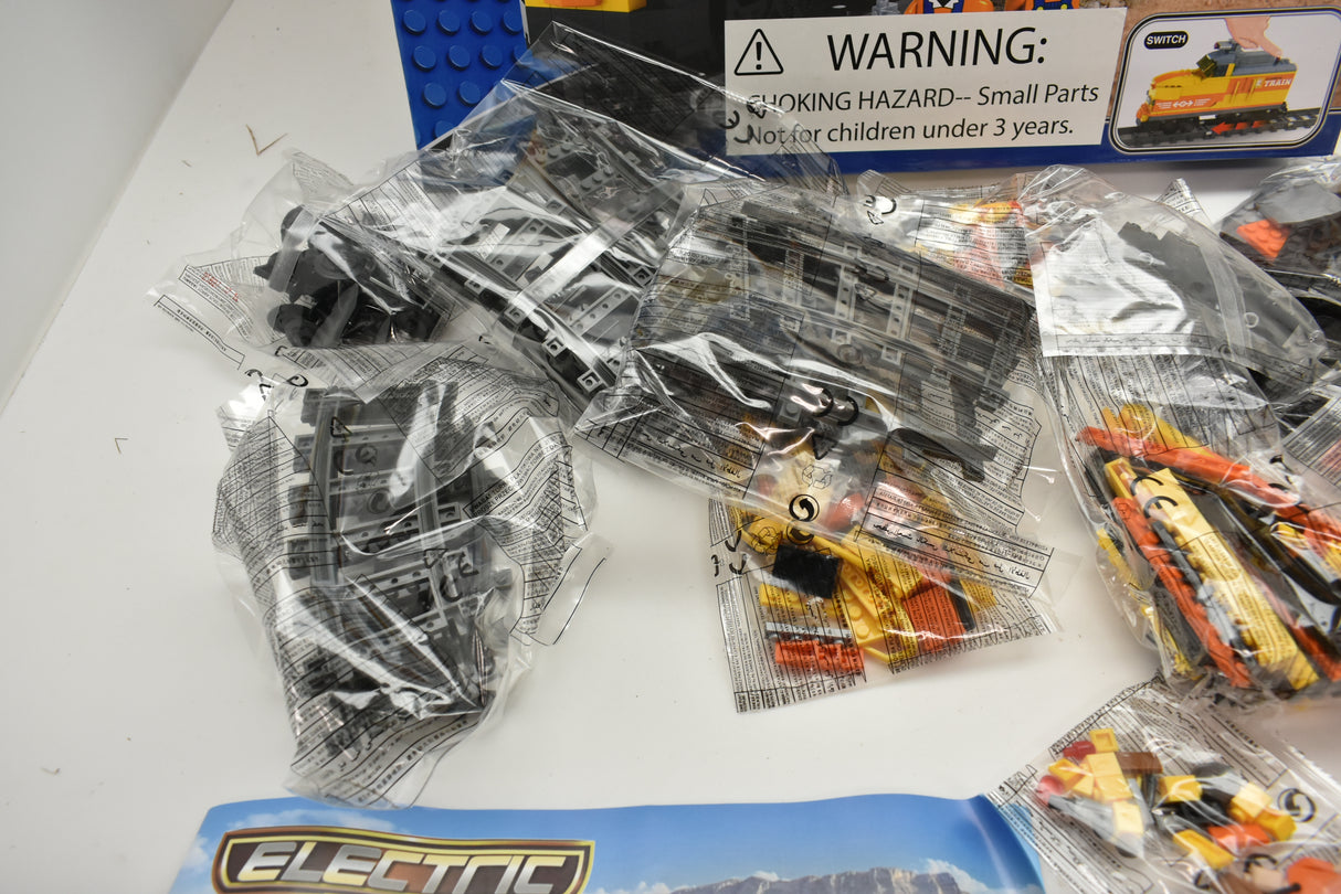 Plastic train parts in clear bags, including a warning label for Electric Train AUS25827