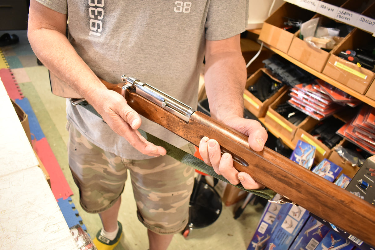 Man holding a wooden trainer rifle, showing its length and metal barrel for Parris Toys M-30b Trainer Rifle