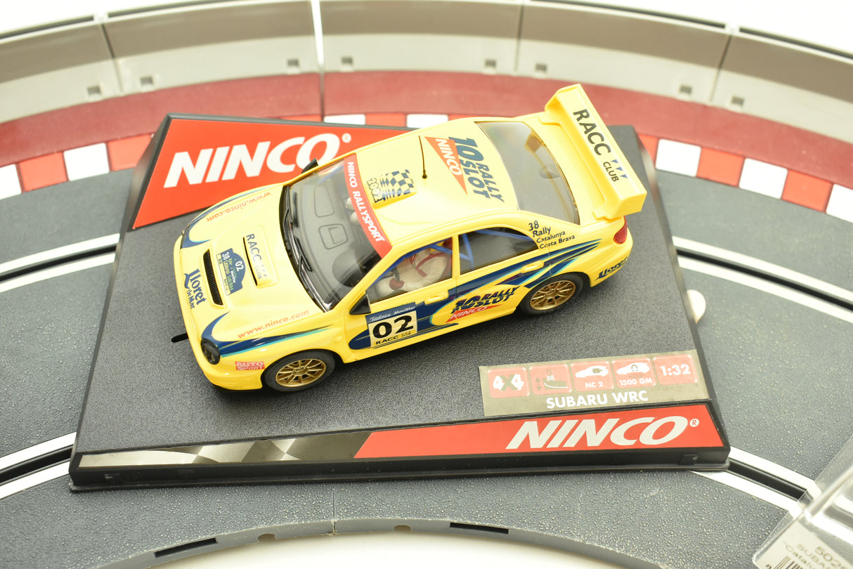 Yellow Subaru WRC slot car on a display base for Ninco 50257