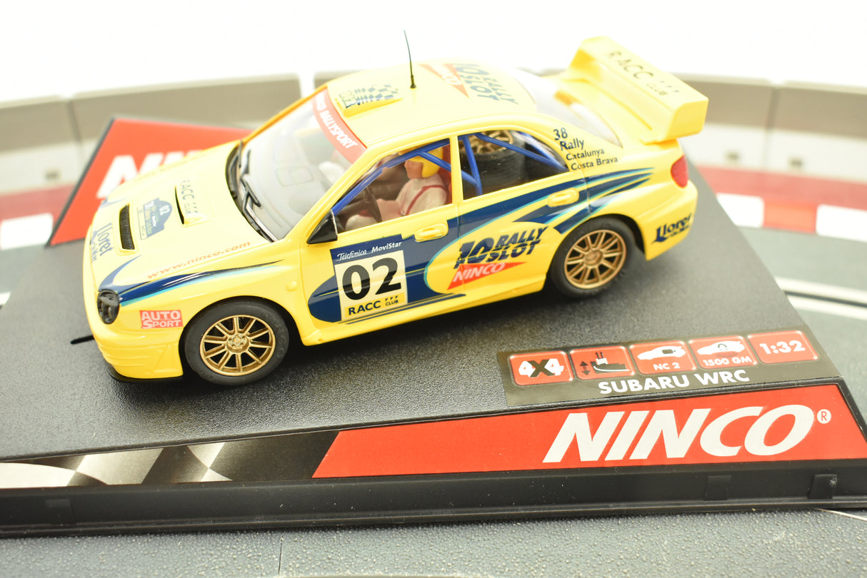 Yellow Subaru WRC slot car on a black display base for Ninco 50257