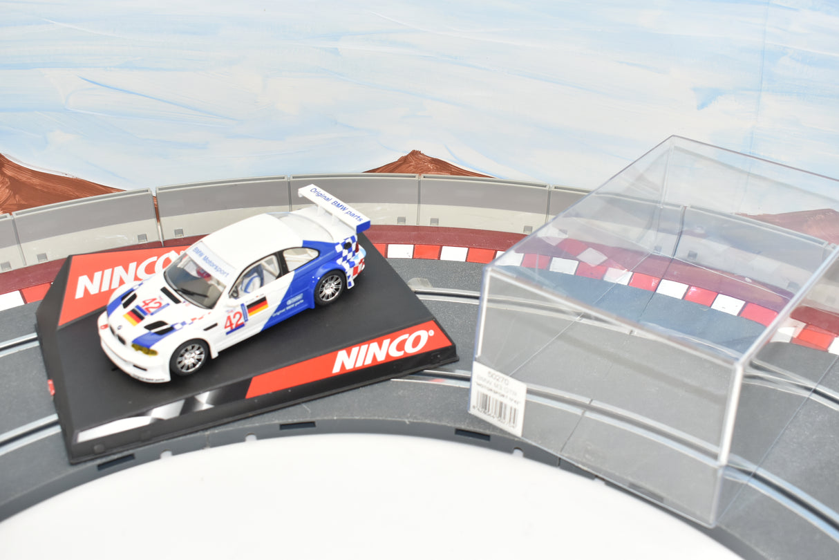 White BMW race car model on a track section with red and white curbing for Ninco 50270