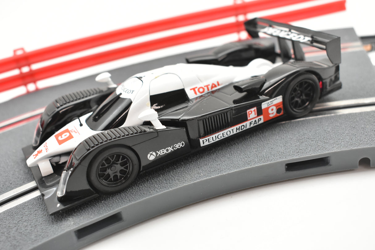 Black and white slot car replica of a Peugeot 908 HDI FAP race car for SCX A10300X3U0, rear view