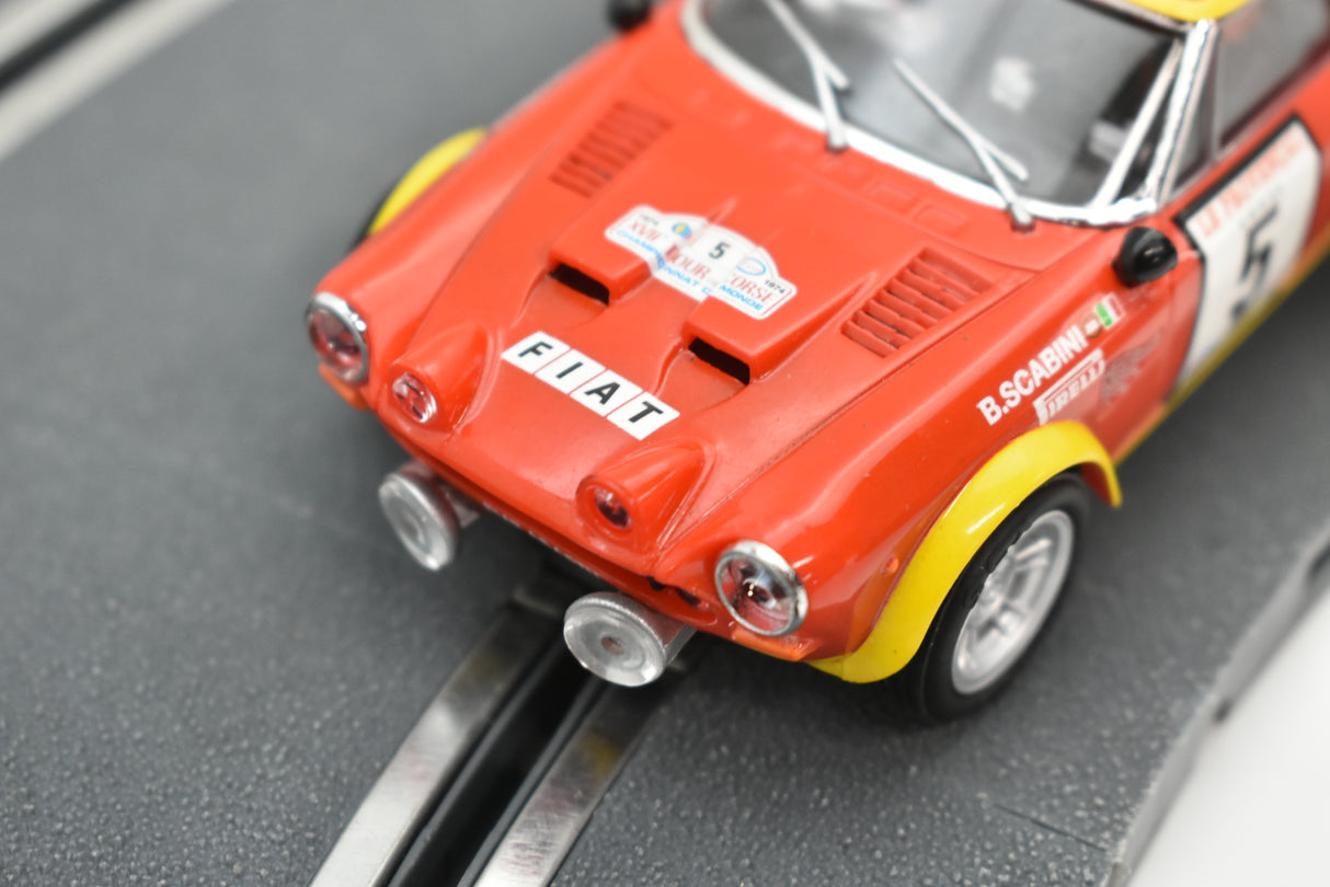 Red Fiat 124 Abarth sport car model on a track for SCX A10220X3U0