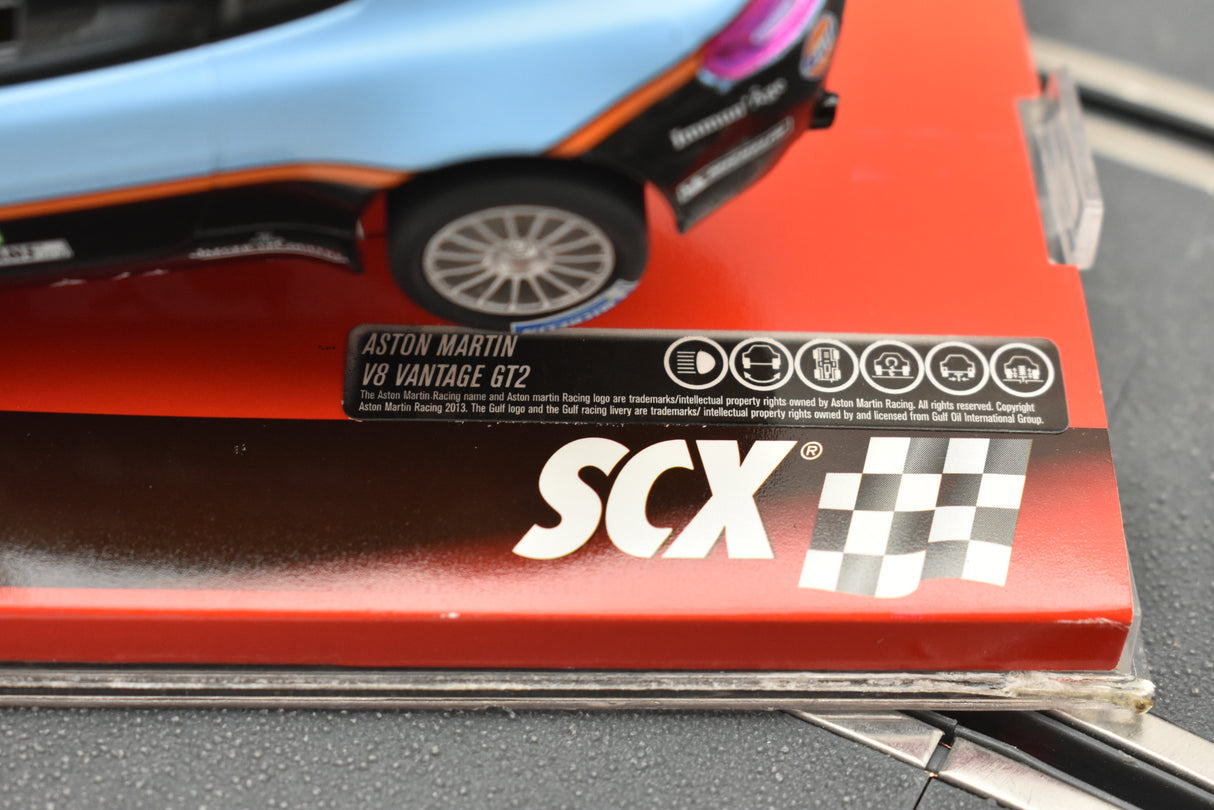 Red box with "ASTON MARTIN V8 VANTAGE GT2" and "SCX" logo for A10116X3U0