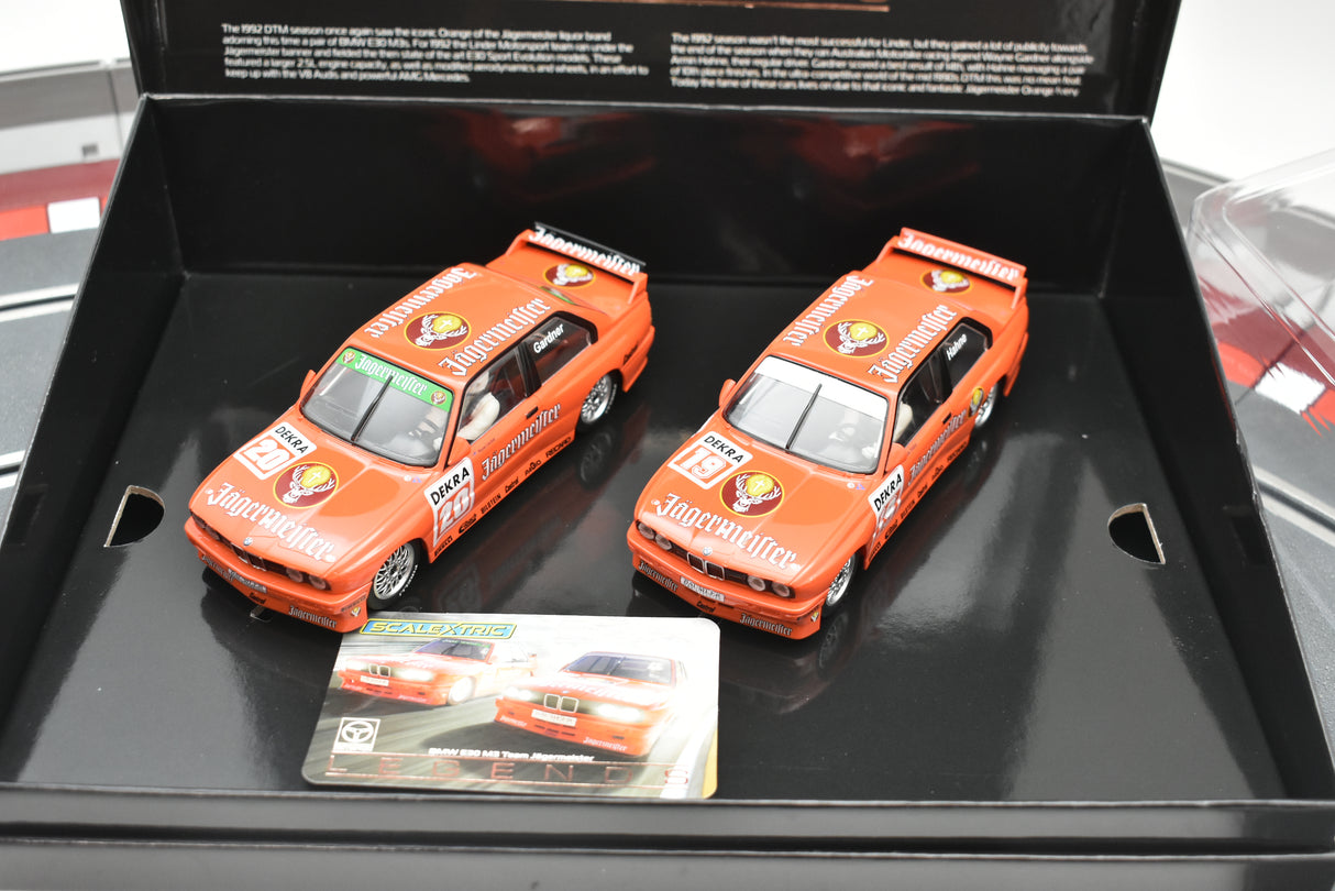 Two orange BMW E30 M3 model cars in a black display box for Scalextric C4110A