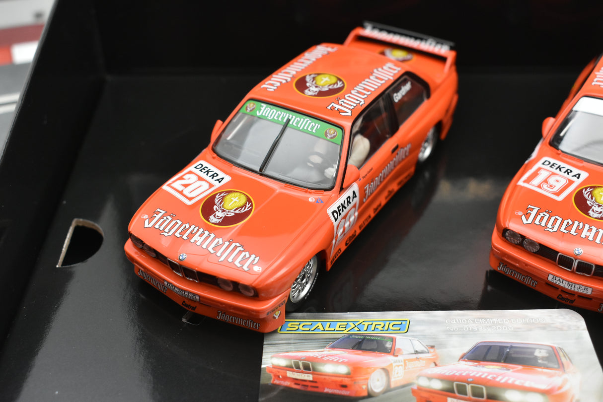 Red BMW E30 M3 slot cars in a display case for Scalextric C4110A