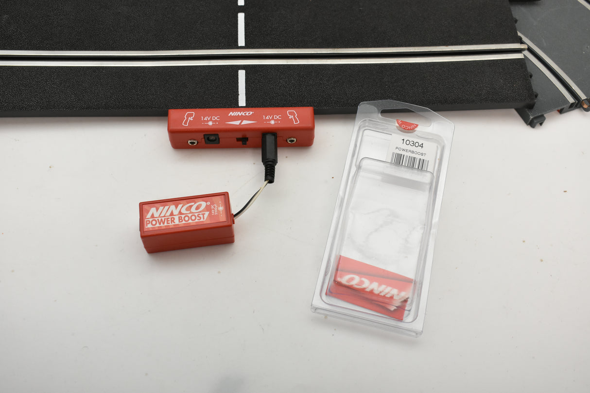 Red power supply units and clear plastic packaging on a white surface for Ninco 10304