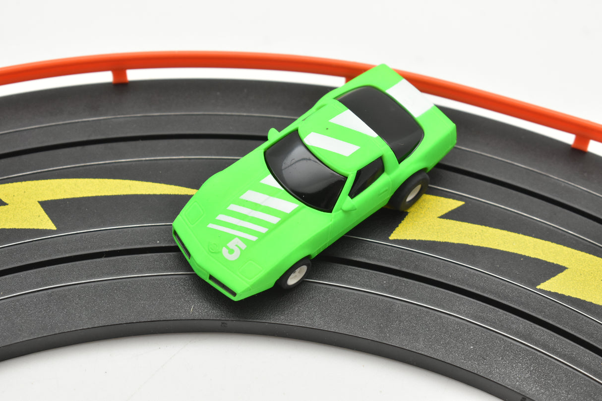 Neon green toy Corvette race car on black and yellow track for Tyco B7057