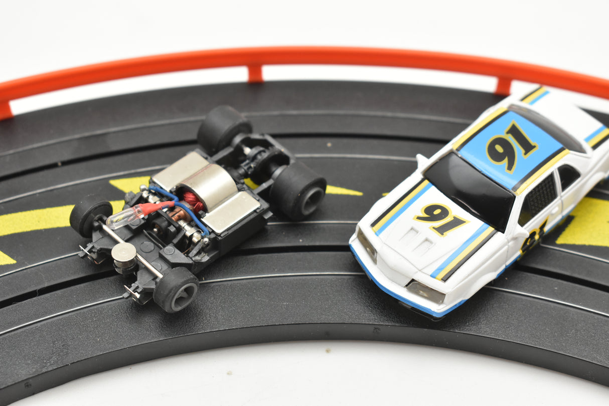 NASCAR race cars on a track: one white/blue/yellow, one black/silver for Life-Like 13016B