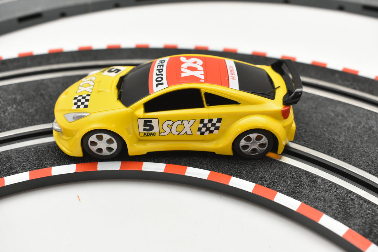 Yellow toy race car with "Repsol" and "SCX" branding on a track for SCX Compact C10182X300