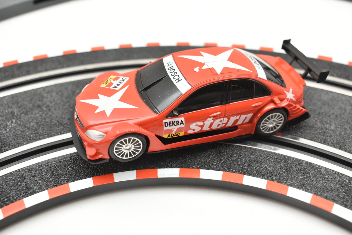 Red slot car on a track, featuring "Stern" branding for SCX Compact C10185X300