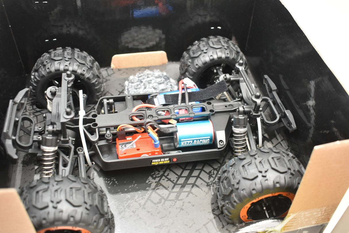 Monster truck components laid out: motor, battery, and large tires for Blue/Yellow IMX19015