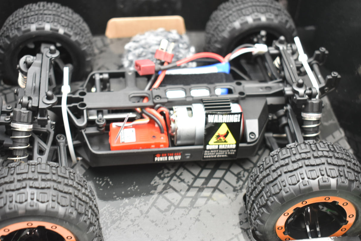 Remote-controlled monster truck with large tires and visible electronics for ORANGE/GREEN IMX19025, side view