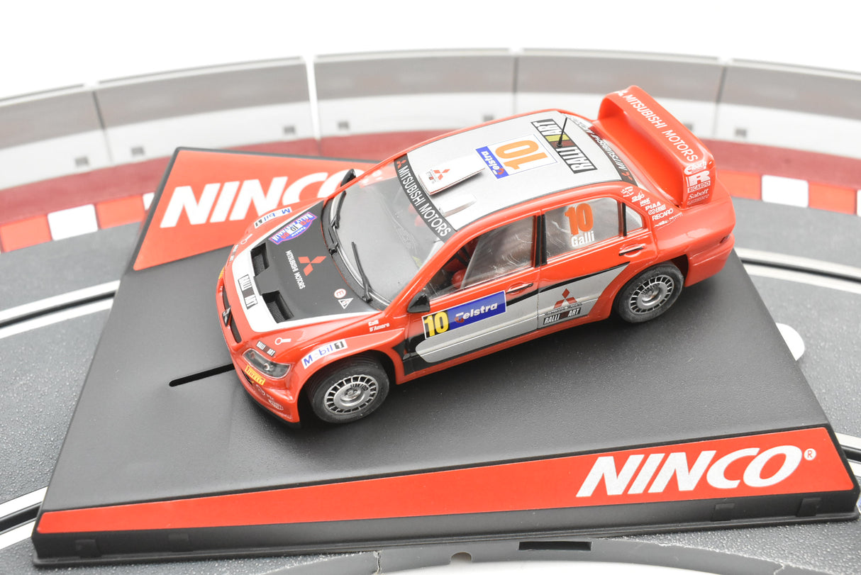 Red Mitsubishi Lancer WRC slot car on a track base for Ninco 50378