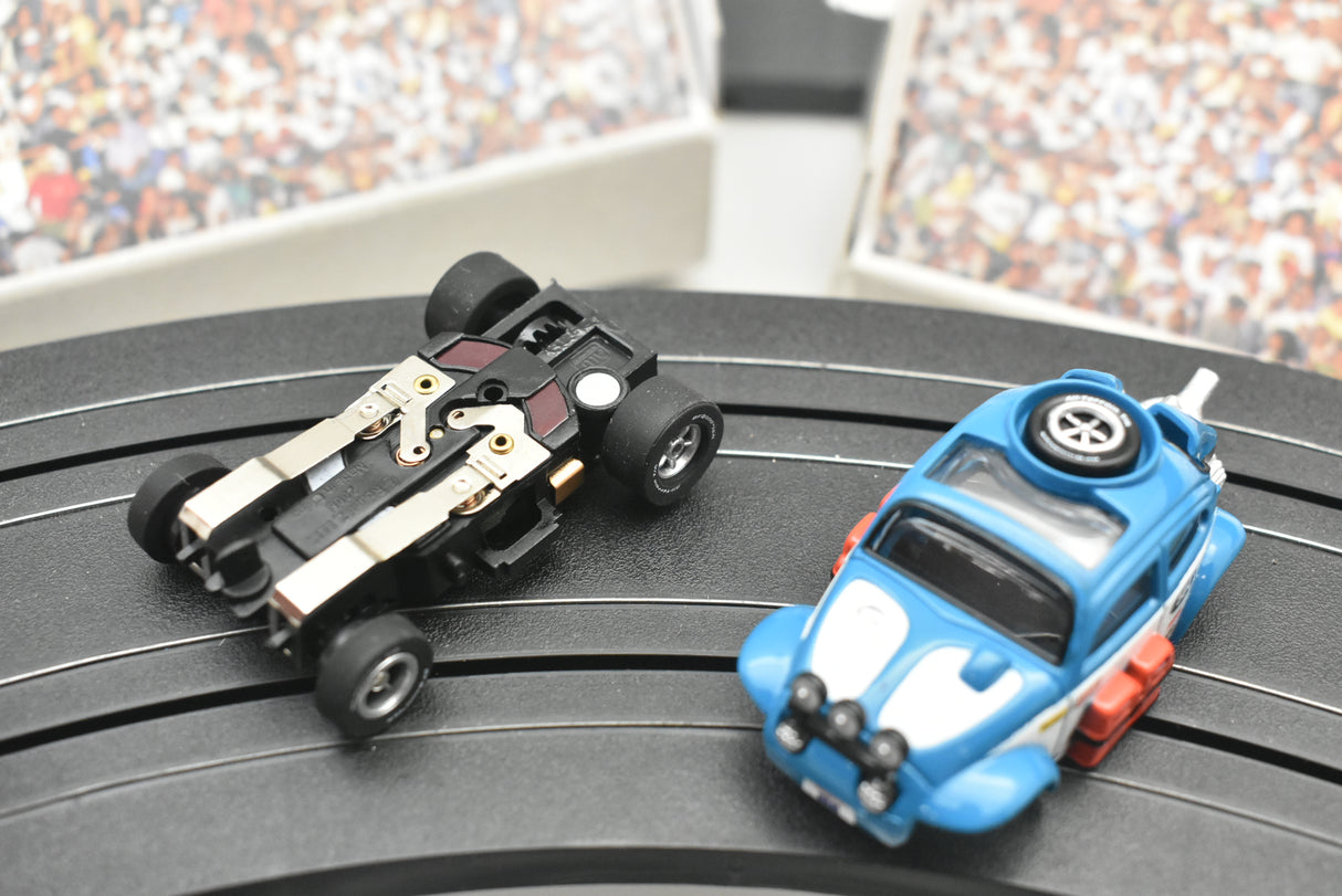 Two slot car VW Beetle cars on a black turntable: one black, one blue for Auto World SC012