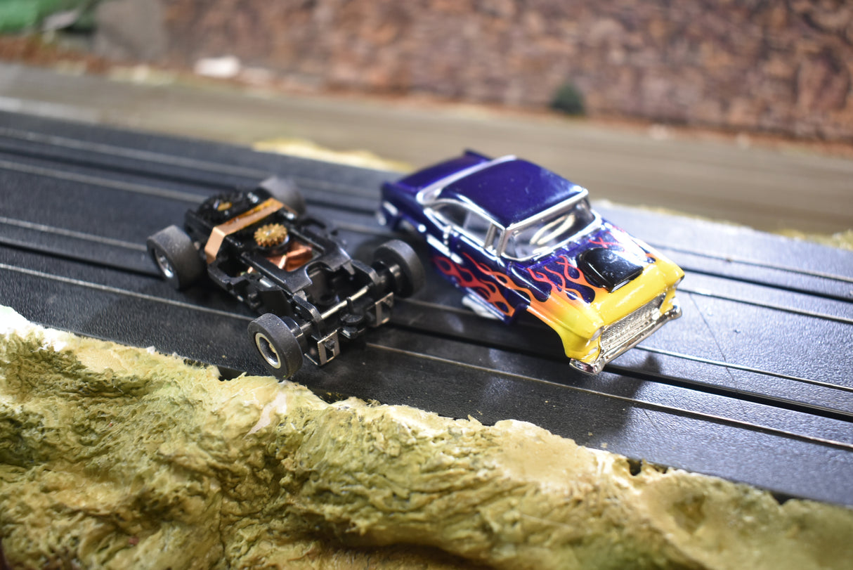 Two slot cars on a track: a black hot rod and a blue Chevy Bel Air for Slot Car 1:64 CP7726