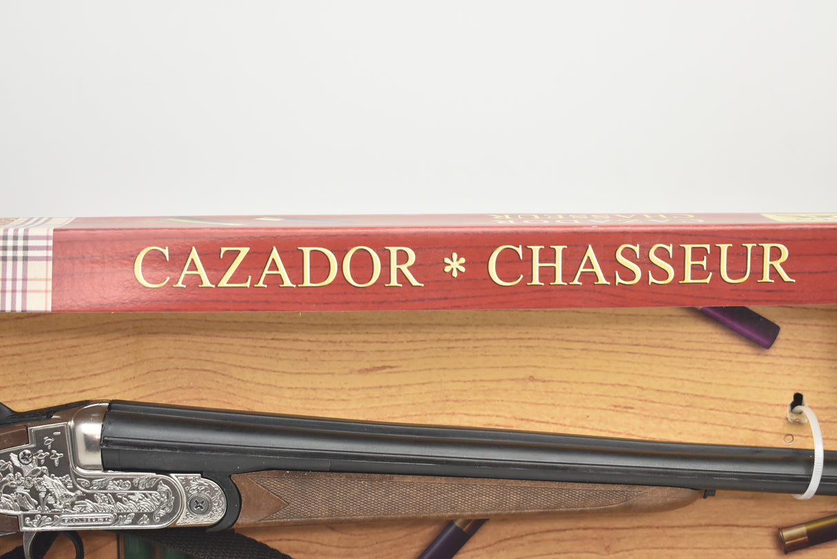 Side-by-side shotgun resting on a book titled "CAZADOR * CHASSEUR" for Gonher 111/0