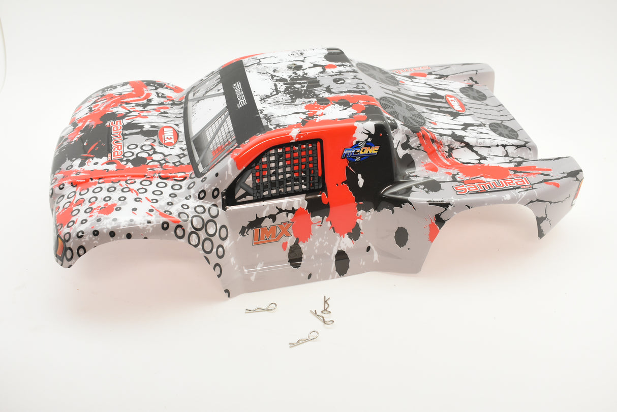 Red and black printed RC truck body shell with small metal parts nearby for IMEX R/C parts IMX18590