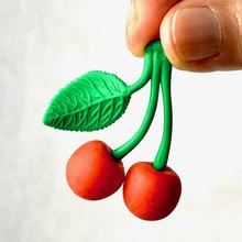 Green leaf and two red cherries eraser, held by fingers for BC Mini 38371