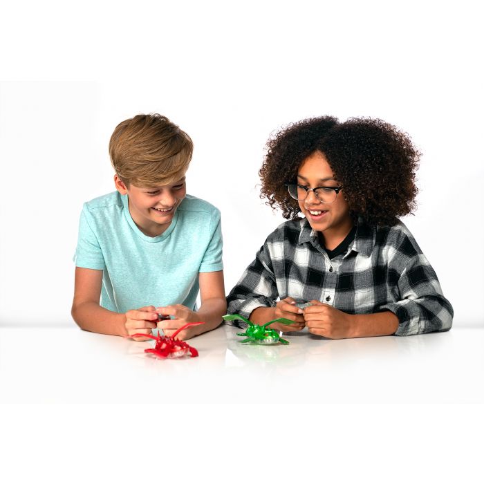 Two children playing with colorful HexBug dragon toys on a white surface for 409-6847