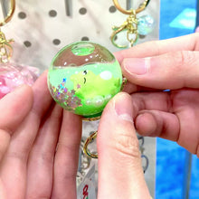 Green, sleeping animal key charm held in hands for BC Mini 12056