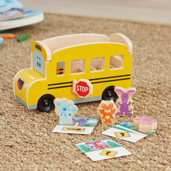 Yellow pull-back school bus toy with animal and clue pieces on wood floor for Melissa and Doug 33011