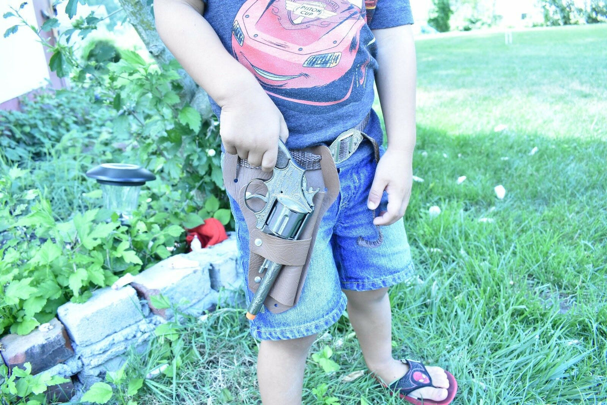 Boy holding a toy pistol and holster set outdoors in the grass for Parris Toys 4711