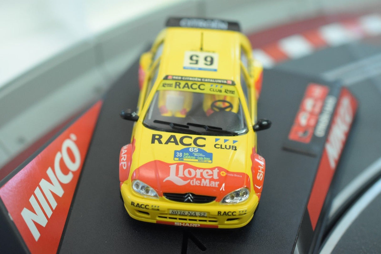 Yellow model car of a Citroen Saxo JWRC, featuring "RACC" decals for Ninco 50266, front view