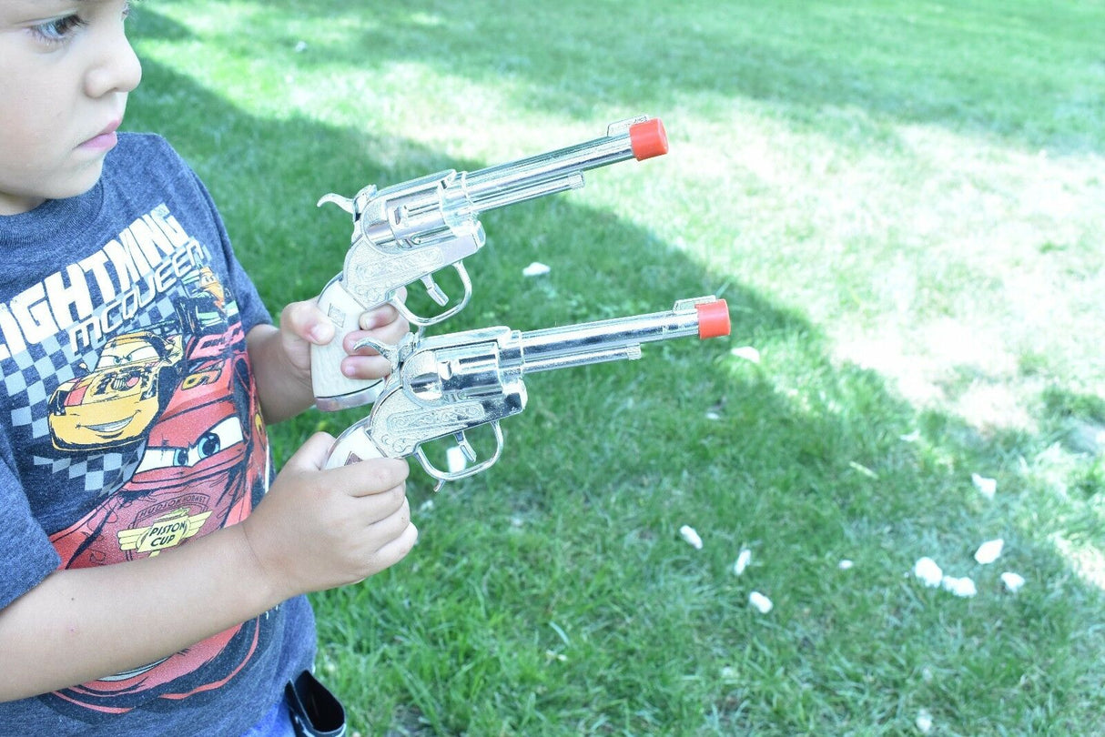 Boy holding two toy western pistols outdoors on green grass for Parris Toys 5506