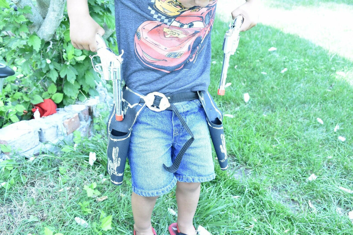 Child holding toy pistols with a gun belt, standing on green grass for Parris Toys 5506