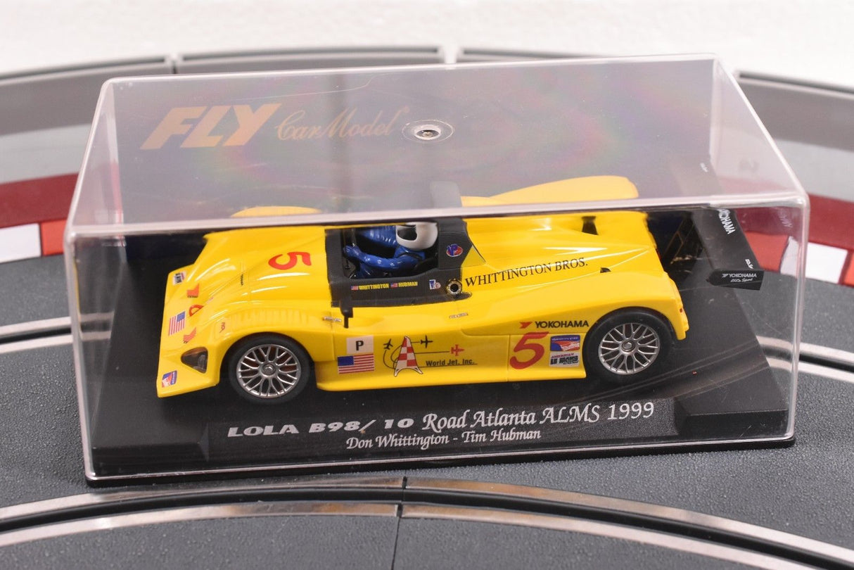 Yellow race car model, Lola B98/10, displayed in clear case for Fly Car 88038