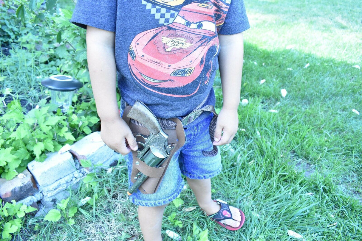 Child holding a toy pistol and holster set outdoors on grass for Parris Toys 4711