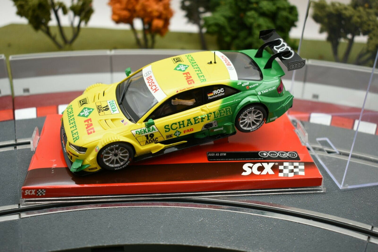 Yellow and green race car model, Audi A5 DTM "Rockenfeller," on a display base for SCX A10161X3U0