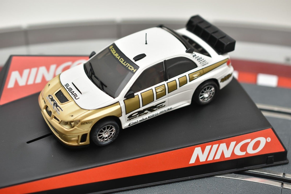 White and gold Subaru race car model on a black and red base for NINCO 50388, rear view