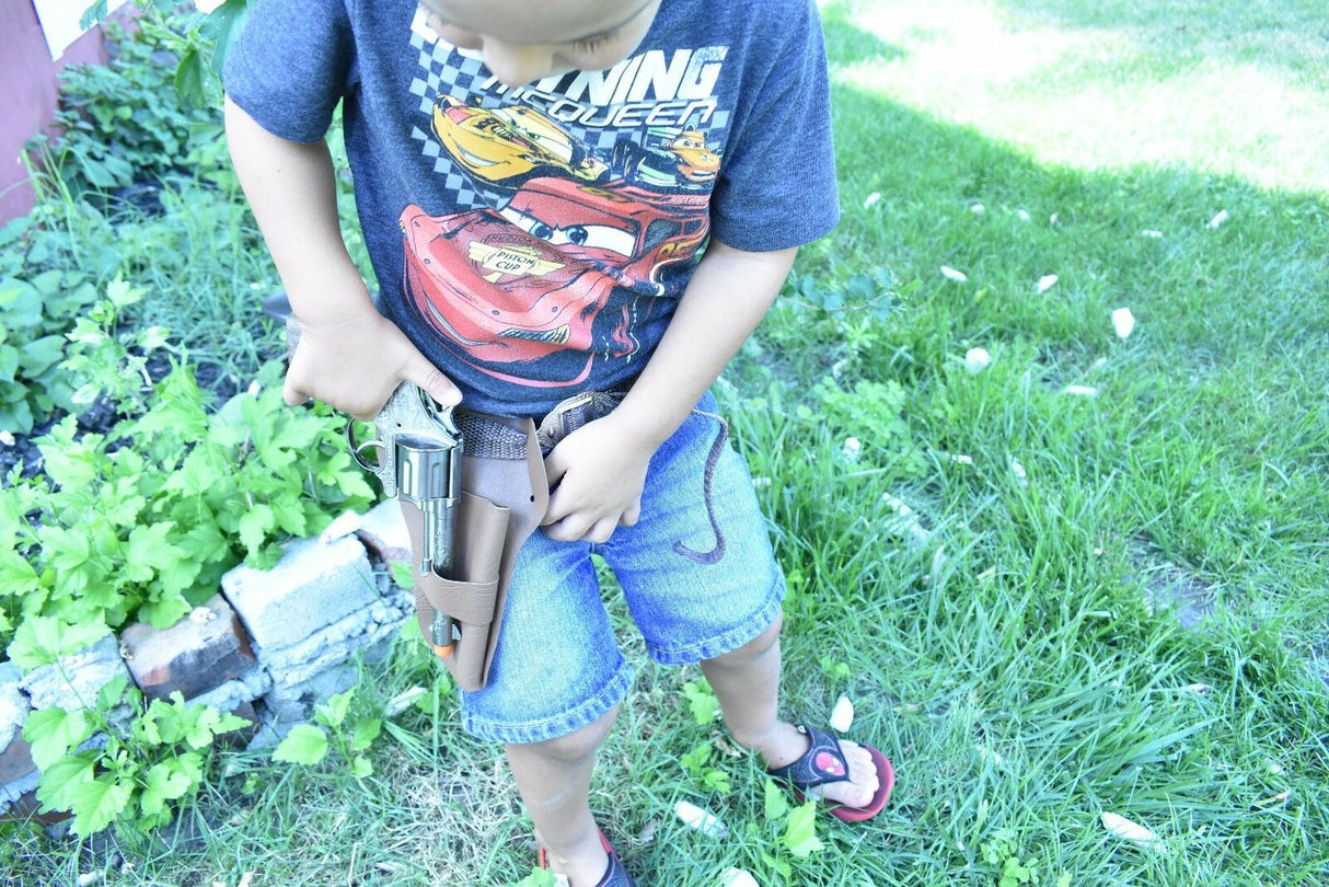 Boy holding a toy pistol and holster set outdoors on grass for Parris Toys 4711
