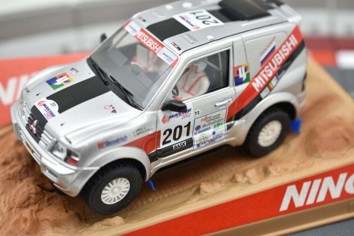 Silver Mitsubishi Pajero race car model on a dirt base for Ninco 50314