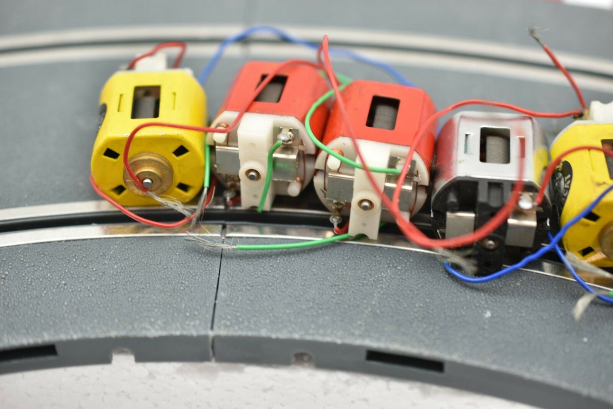 Row of small electric motors with attached wires on a gray surface for Mabuchi 8-Motors