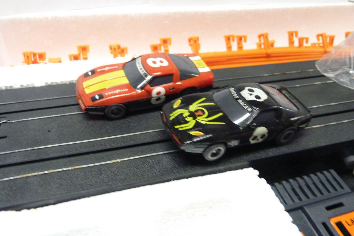 Two slot car race cars on a black track section for Aurora Tomy AFX Vintage 8607M