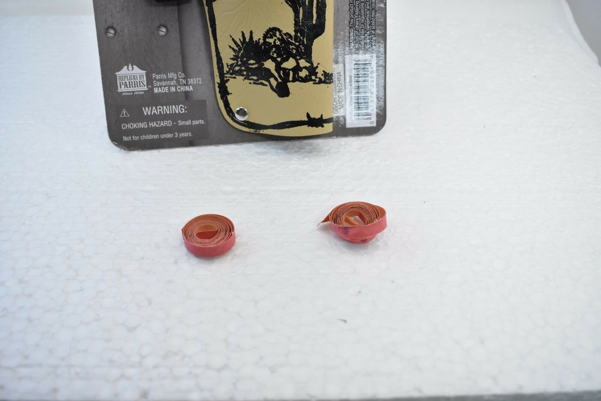 Two red, rolled-up items on a white surface near a holster packaging for Parris Toys 5504