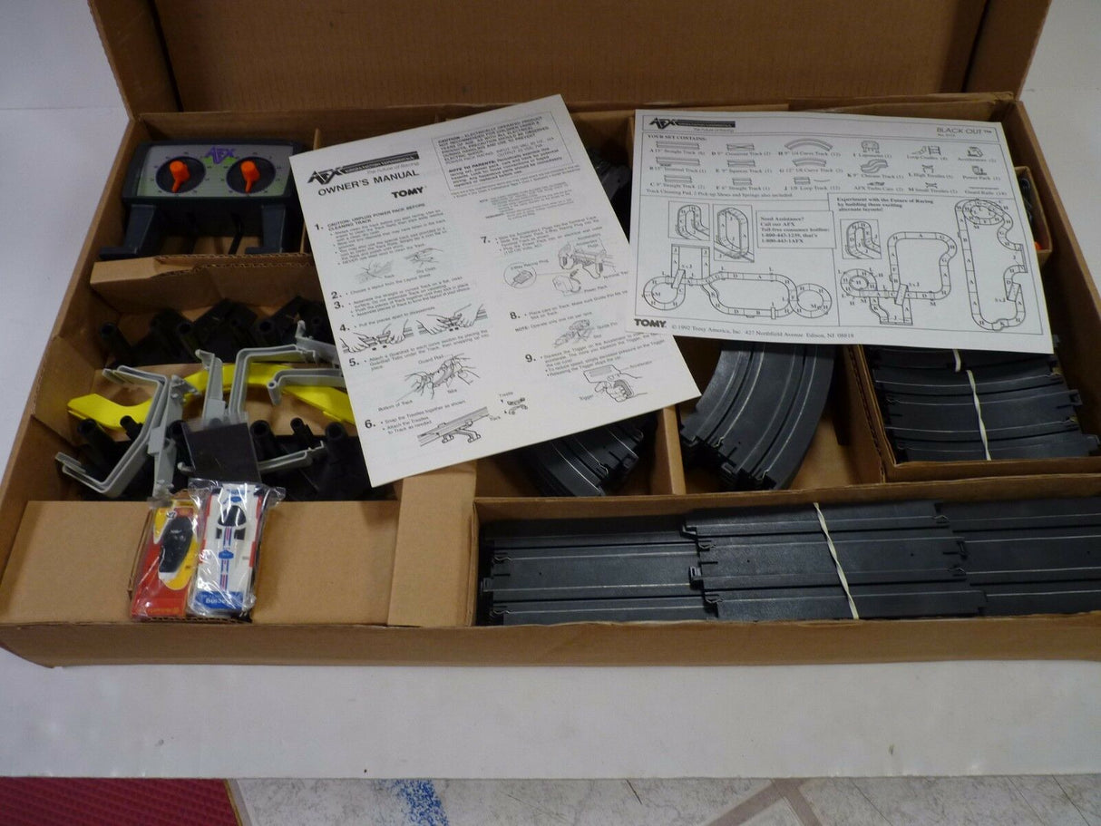 Race set components laid out in an open cardboard box for Aurora / AFX / Tomy 9115M