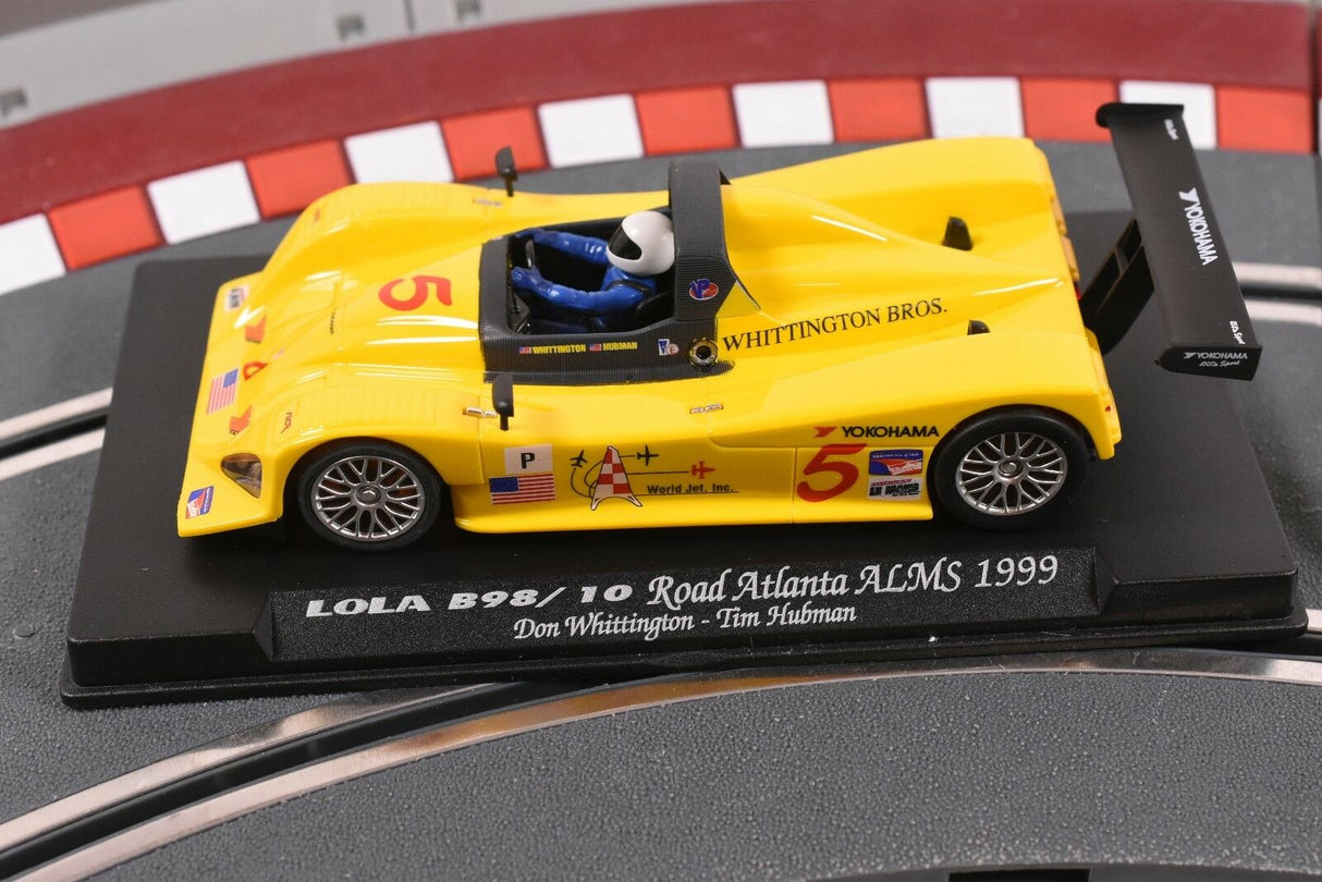 Yellow race car model, LOLA B98/10, displayed on a black base for Fly Car 88038